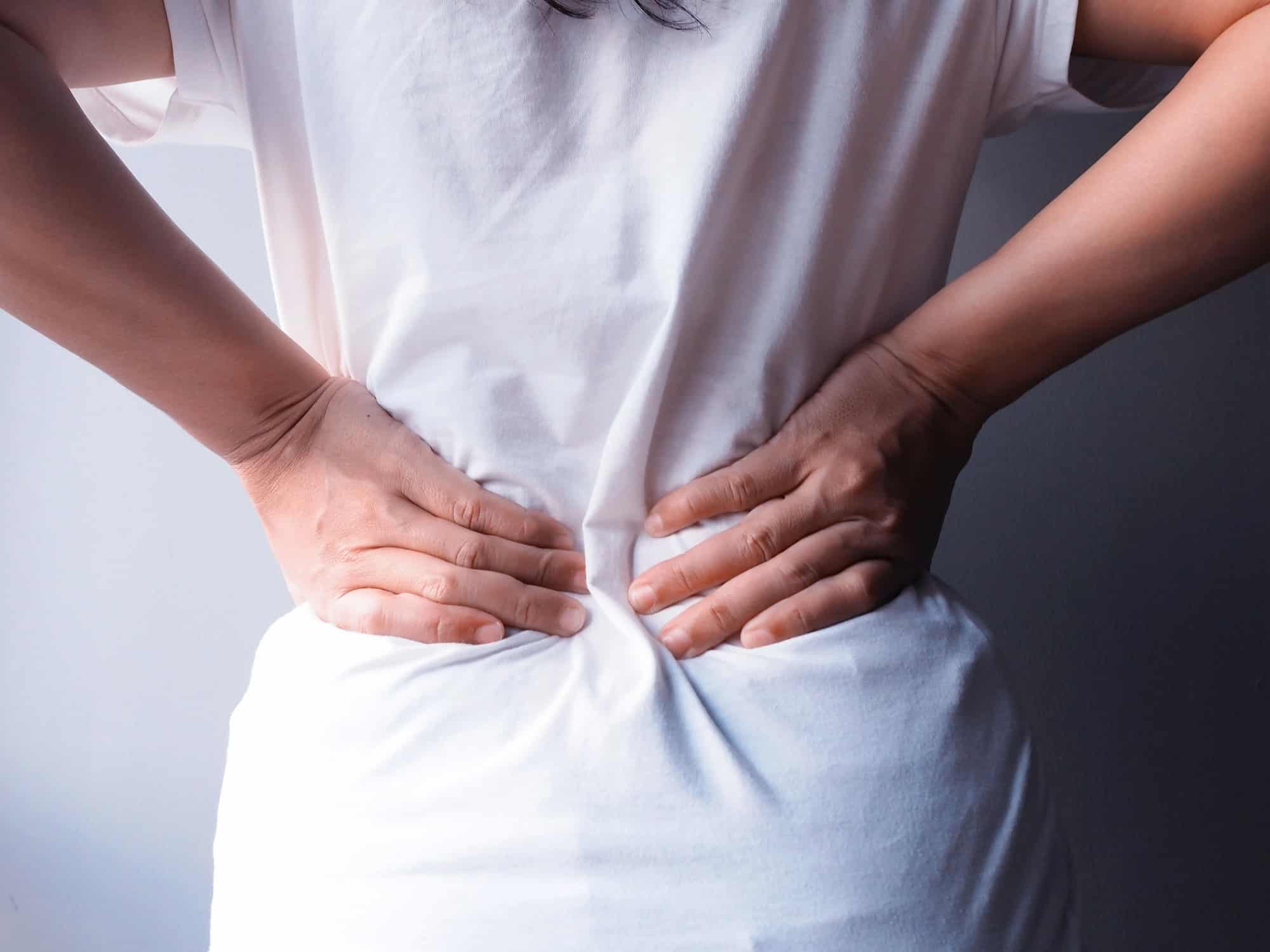 Asian woman suffering from back pain and waist, Have symptoms muscle injury or chronic nerve pain.