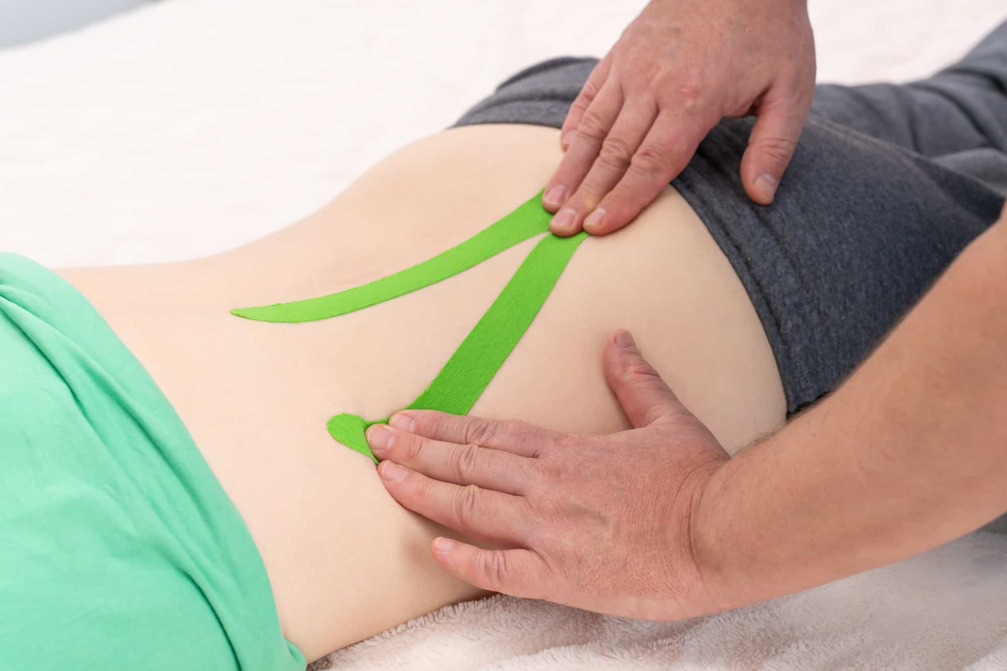 Osteopath applying kinesiology taping to a patient with back pain