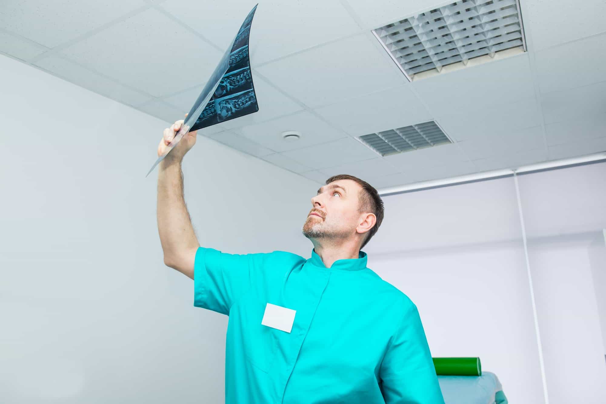 Doctor looking at an x-ray image of the patient's spine. Osteopathy, chiropractic, physiotherapy.