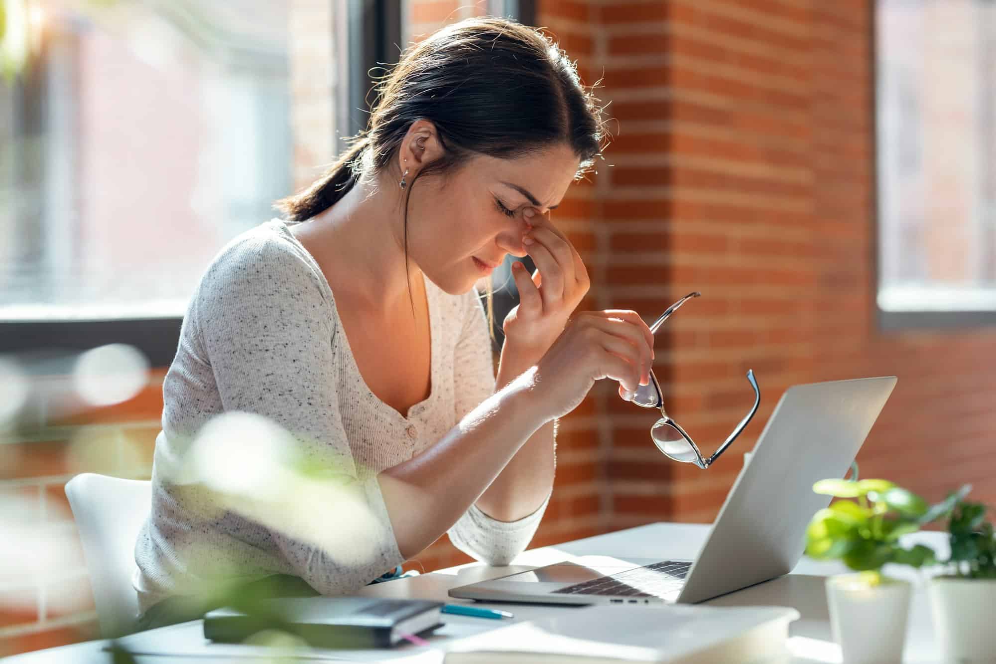 Tired business woman with headache looking uncomfortable while working with computer in the office