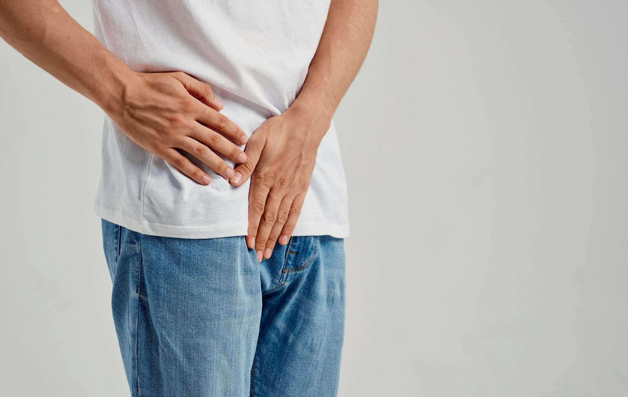 man experiencing pain below the belt in the groin and jeans t-shirt model