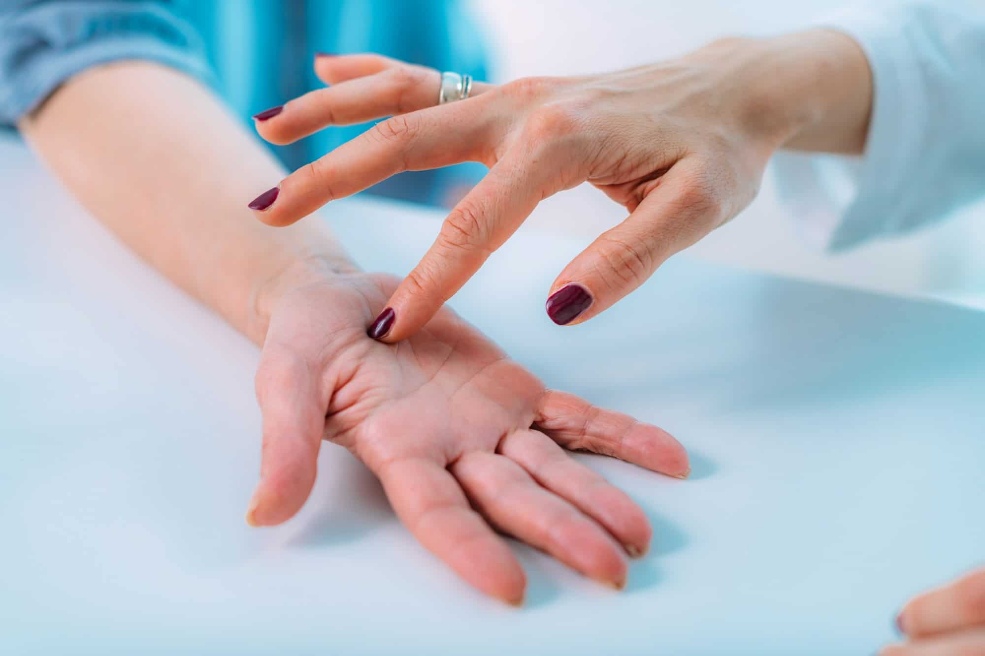 Examining the hand of a senior patient with carpal tunnel syndrome.